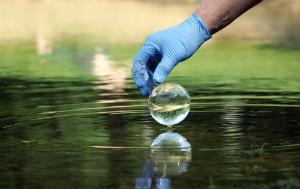 Water sample. Hand in glove collects water